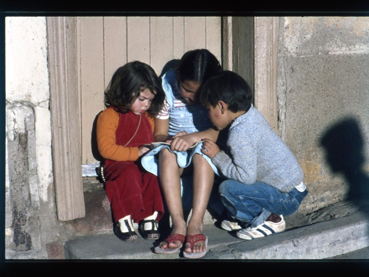 Niños haciendo tareas escolares en la puerta de su casa / Cerro Cordillera