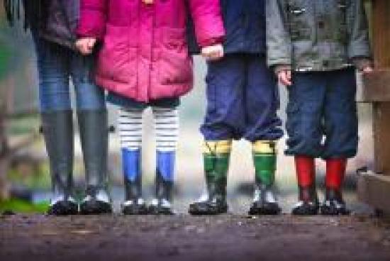 Imagen de pies de niños con botas de agua y ropa de abrigo